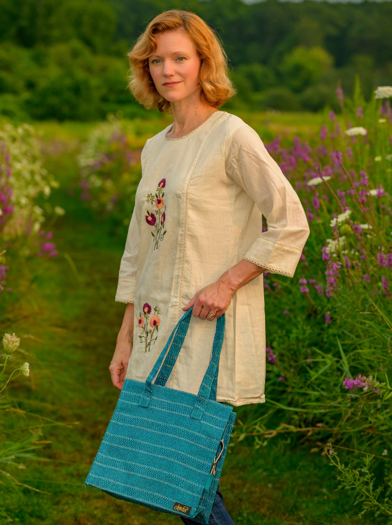 Woman holding a blue bag in a field of flowers