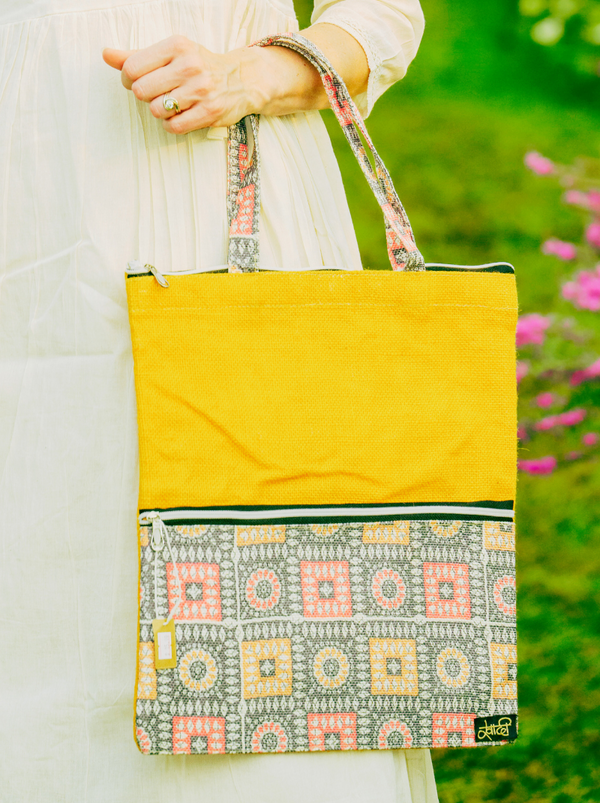 Person holding a yellow tote bag with patterned design