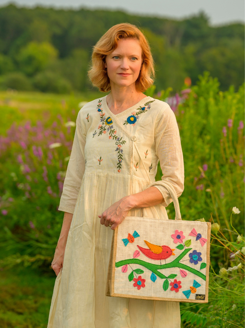 Woman holding a embroidered bag in a field with flowers