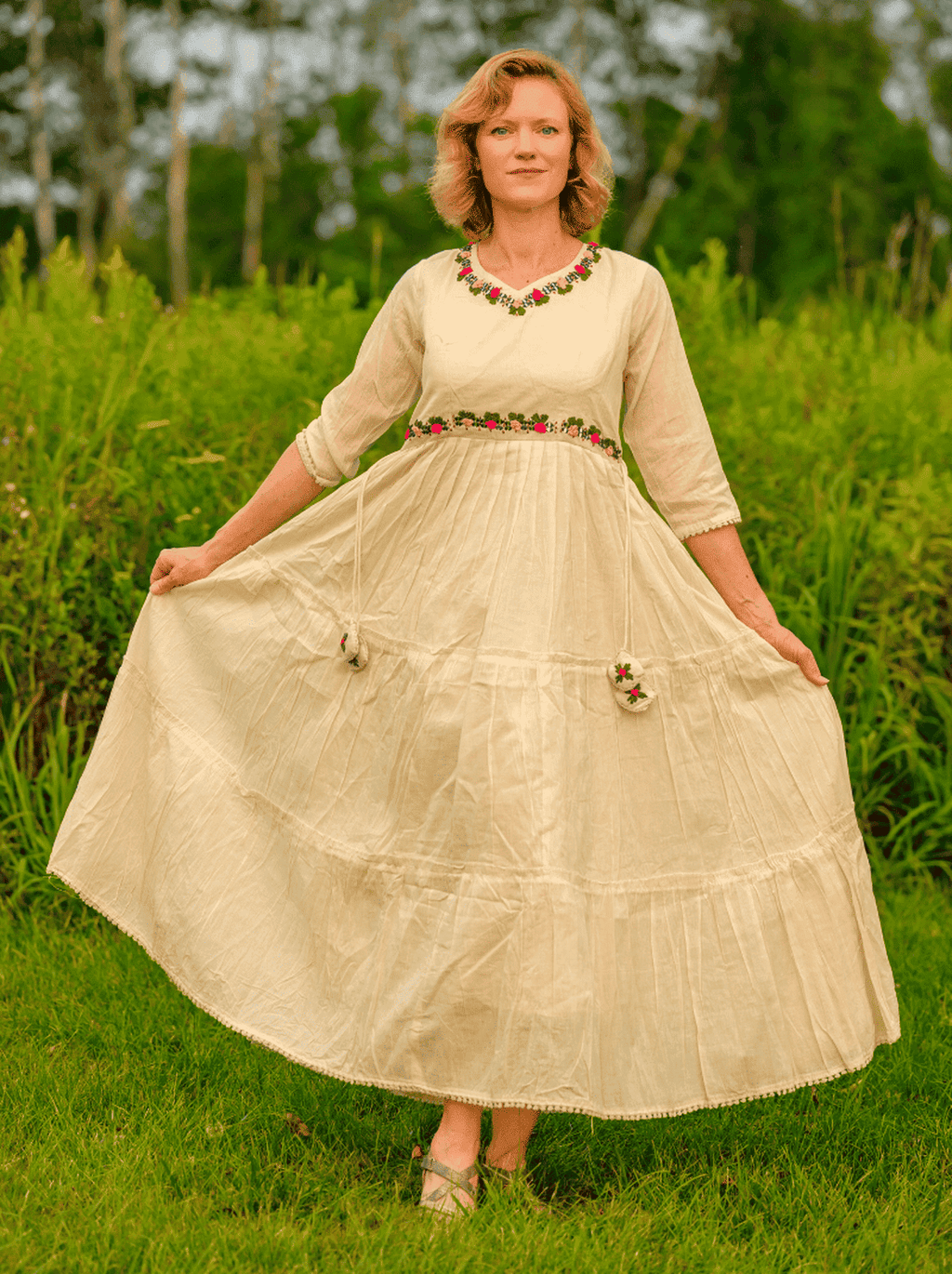 Woman in a beige dress standing in a grassy field