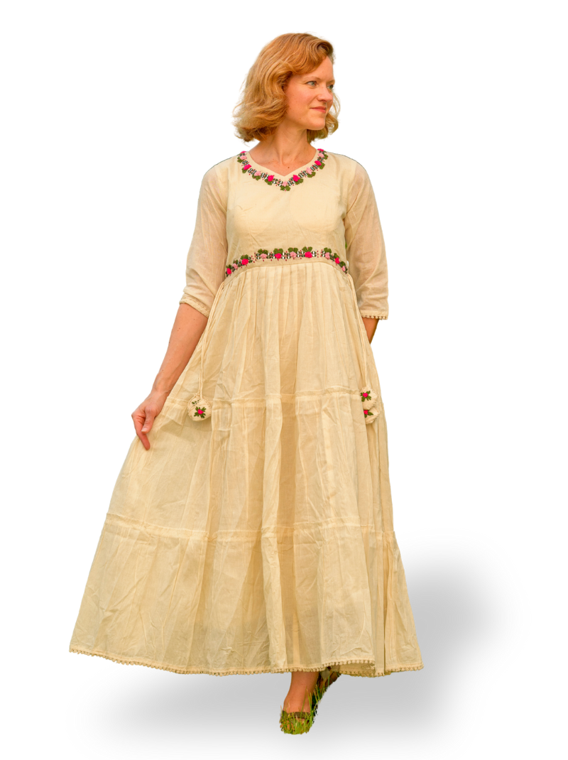 Woman wearing a beige dress with floral embroidery on a white background
