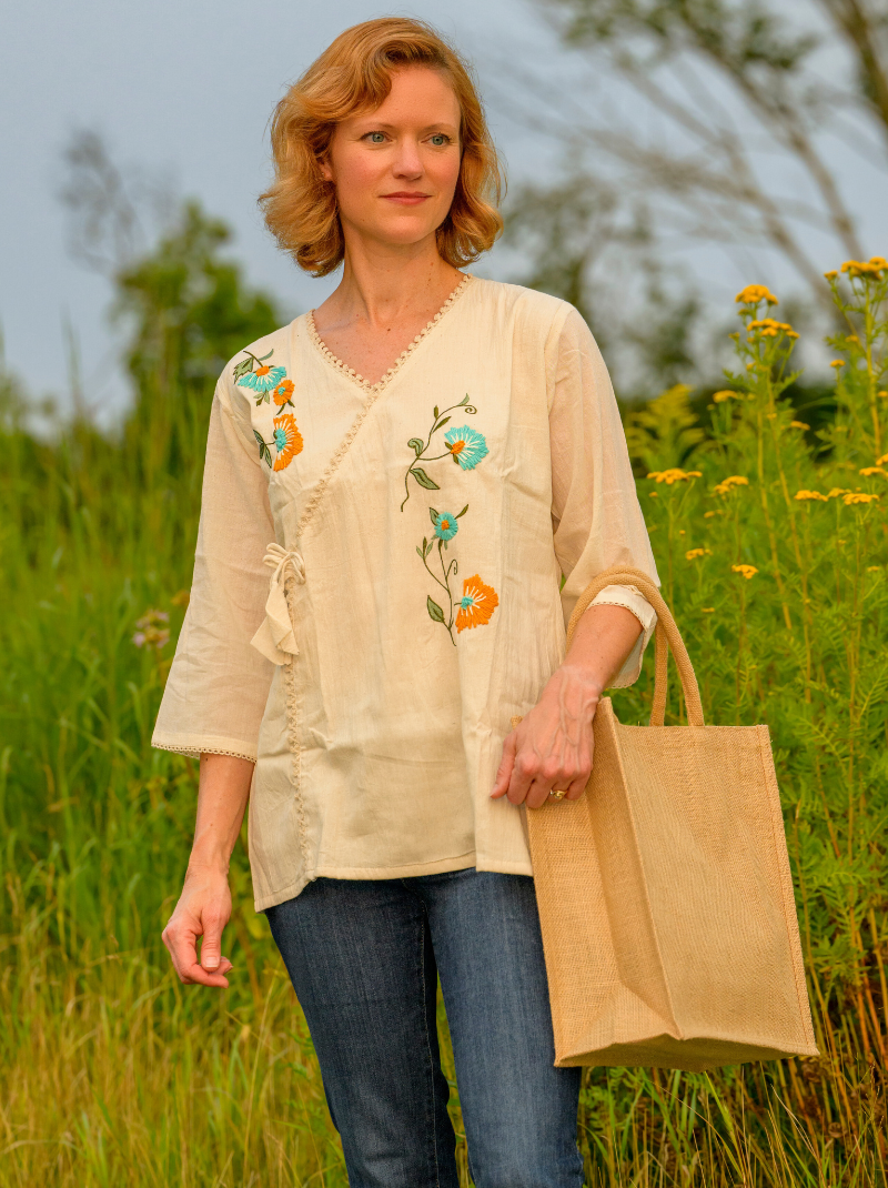 Woman wearing a beige embroidered blouse in a field