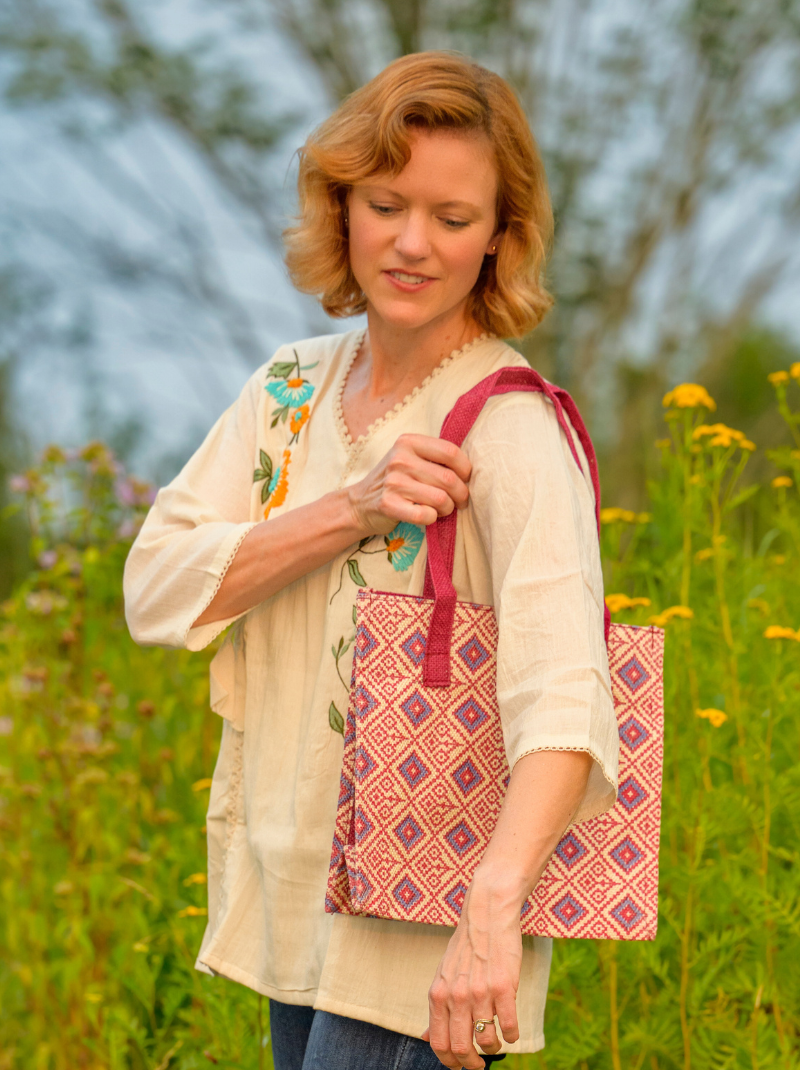 Woman holding a patterned bag in a field with blurred background