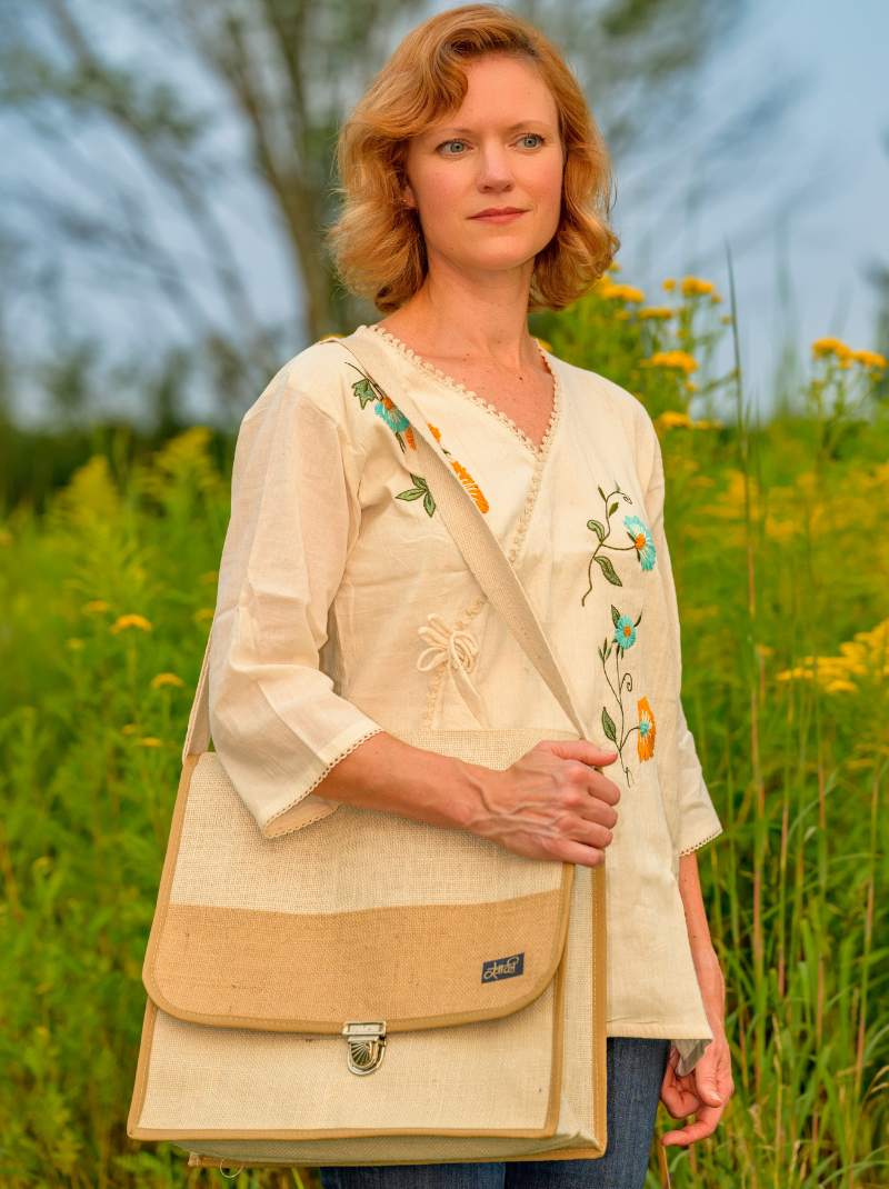 Woman holding a beige and brown bag in a field