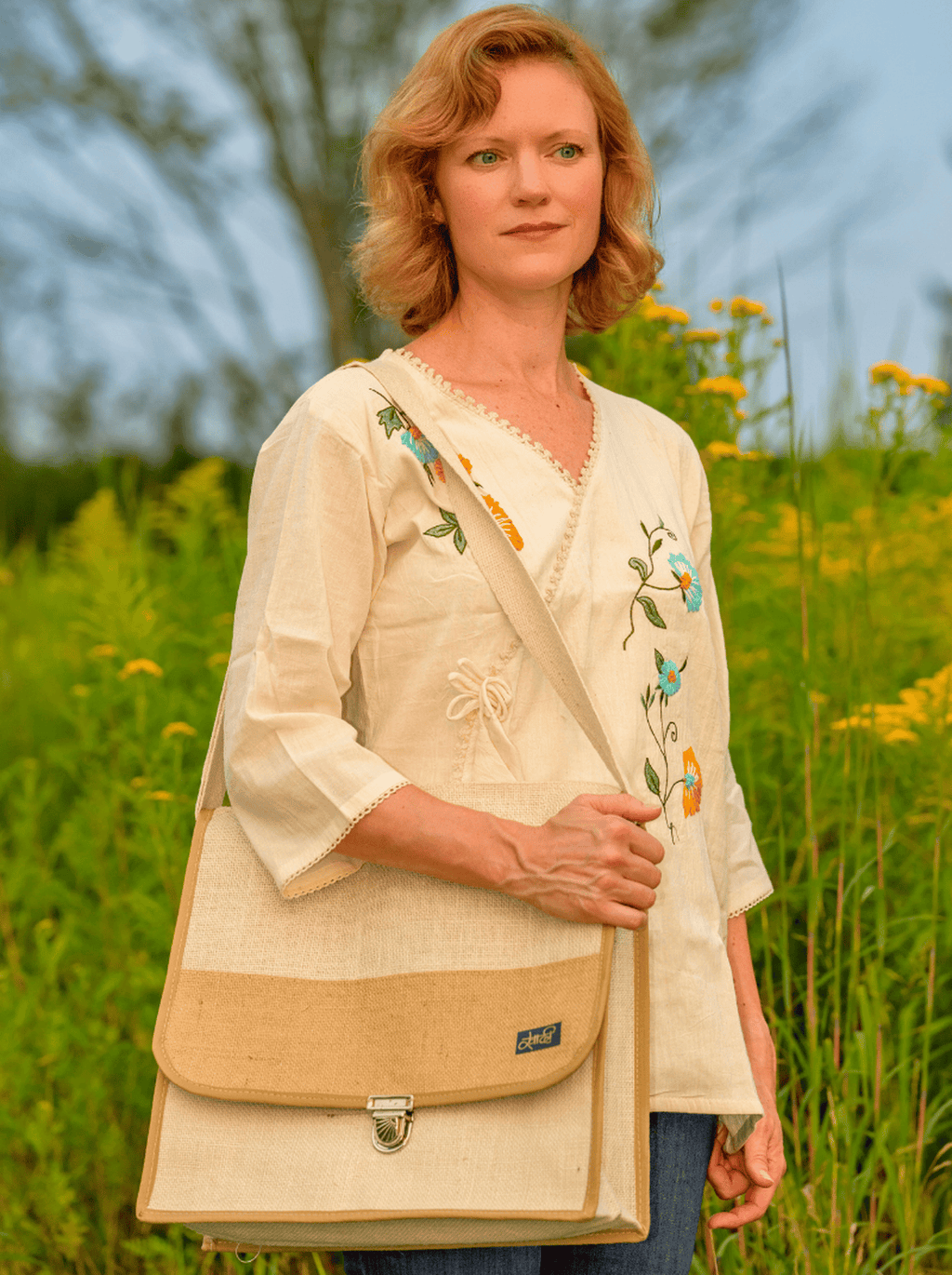 Woman holding a beige and brown bag in a field