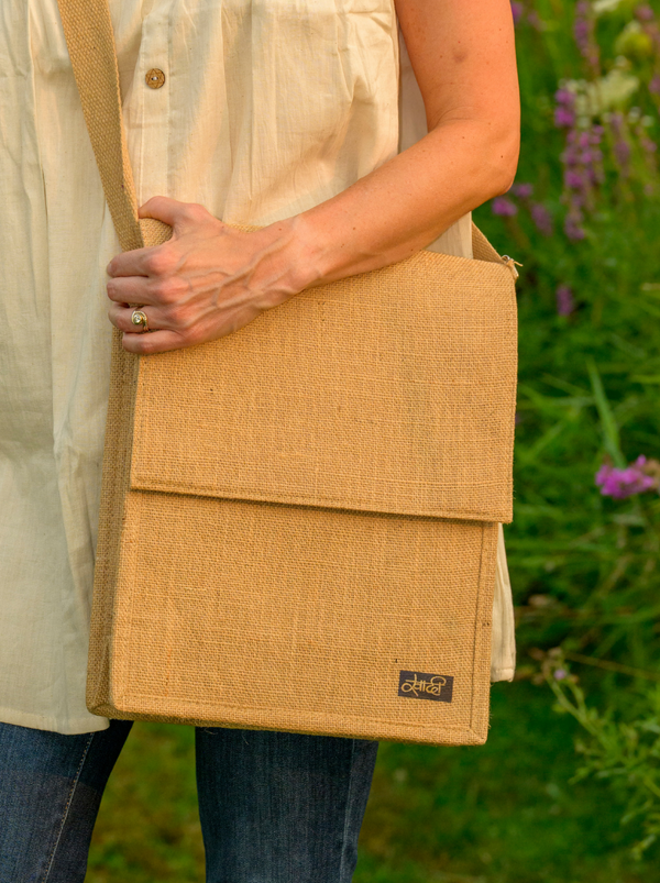 Person holding a beige woven bag with a blurred natural background