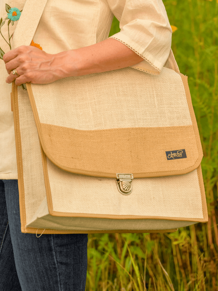 Person holding a beige and brown bag with a blurred green background