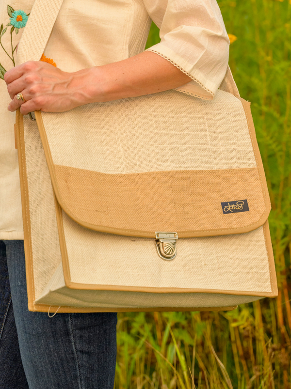 Person holding a beige and brown bag with a blurred green background