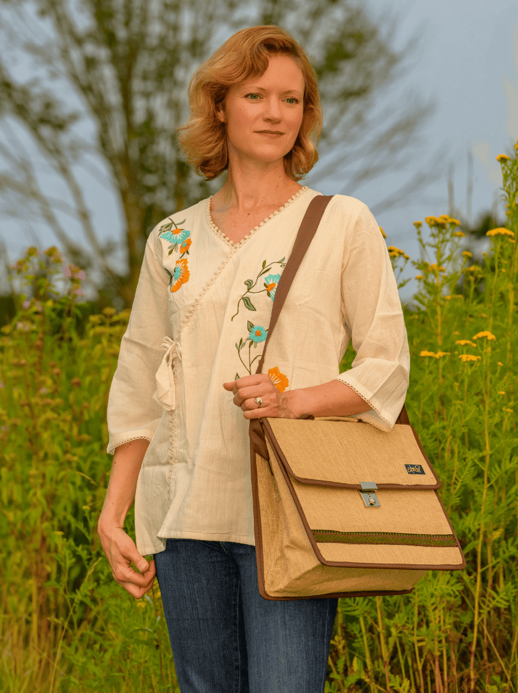 Woman holding a beige bag in a field with wildflowers