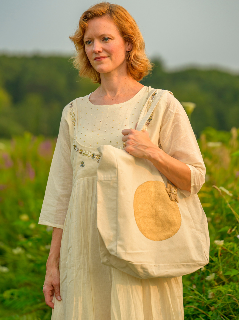 Woman holding a tote bag with a yellow circle in a field