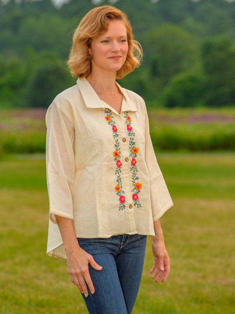 Woman wearing a beige blouse with floral embroidery in a field