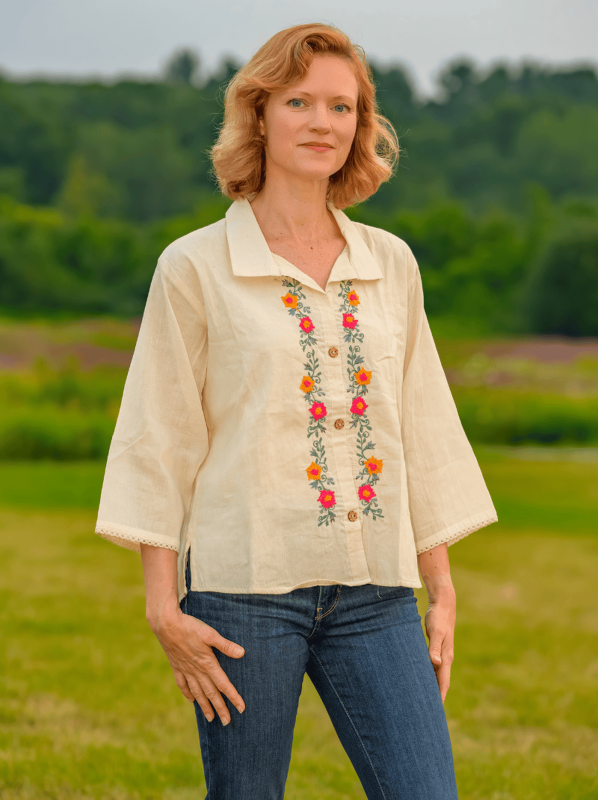 Woman wearing a beige blouse with floral embroidery in an outdoor setting