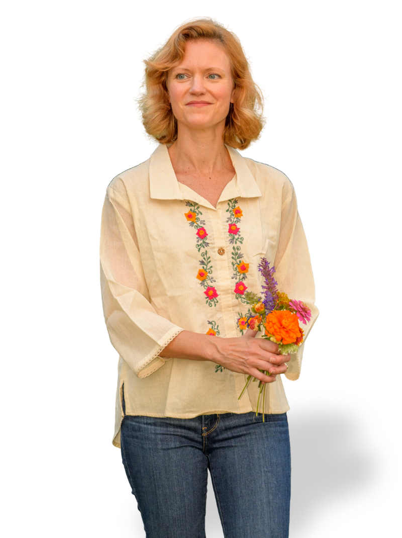 Woman wearing a beige blouse with floral embroidery holding flowers on a white background