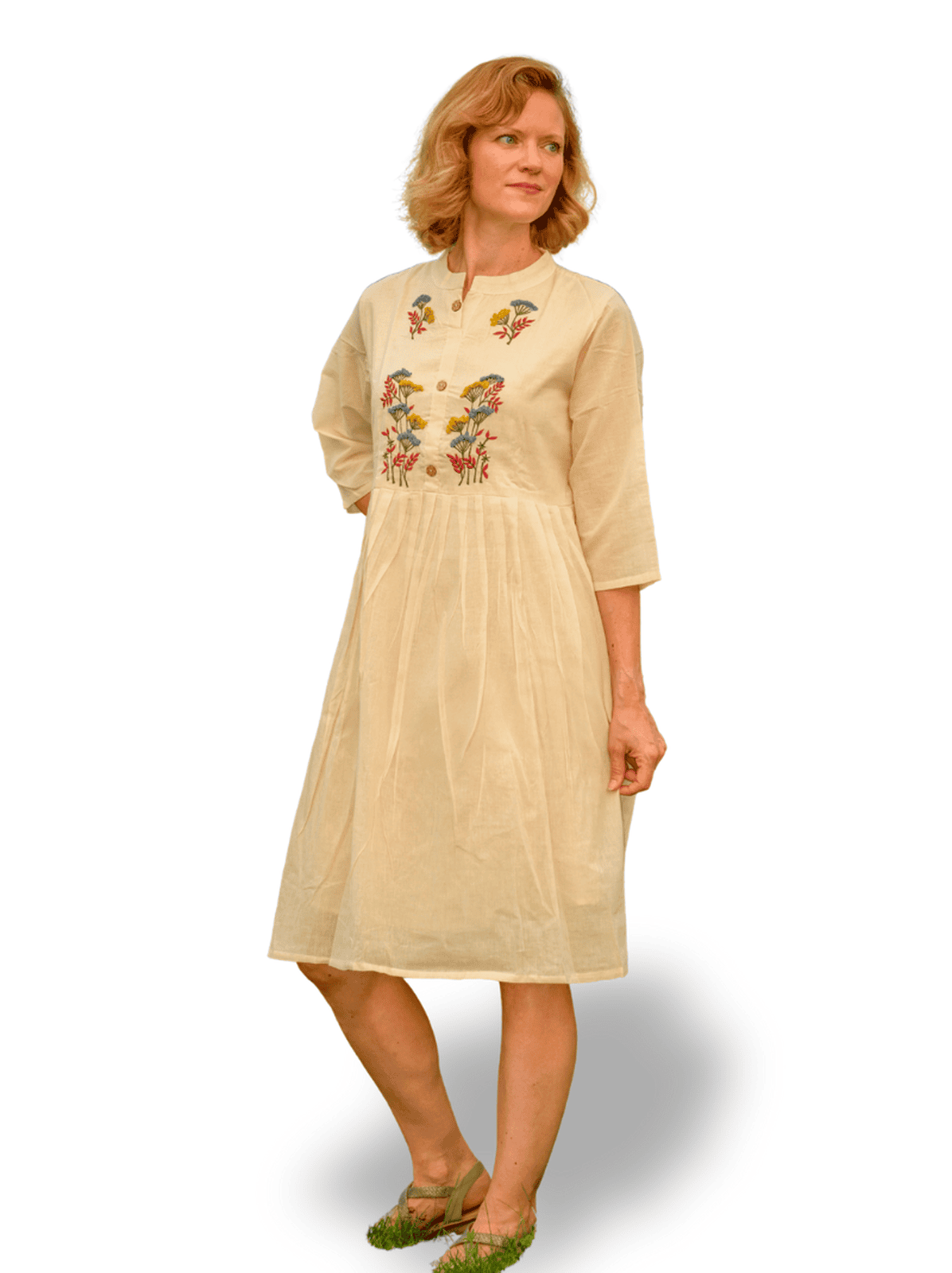 Woman wearing a beige dress with floral embroidery on a white background