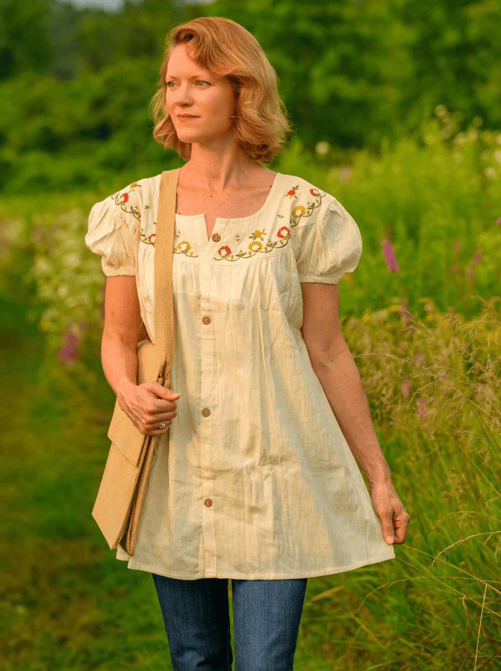 Woman wearing a light-colored embroidered dress in a natural setting