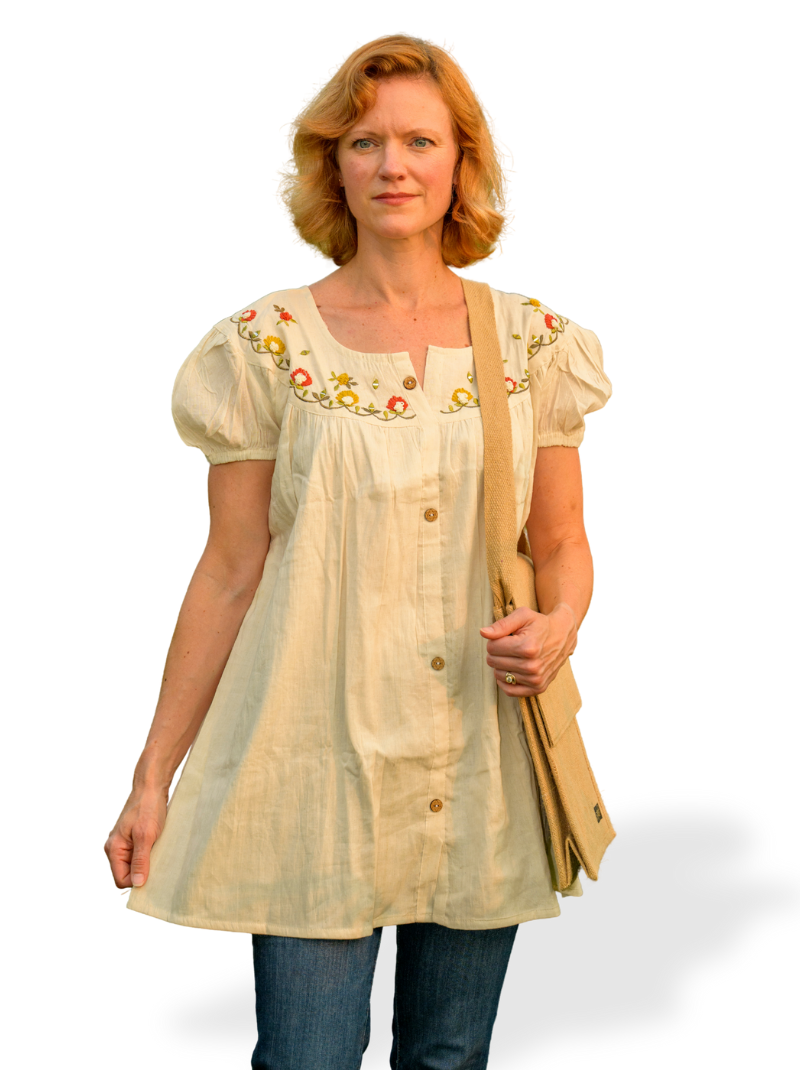 Woman wearing a beige embroidered blouse with a plain background