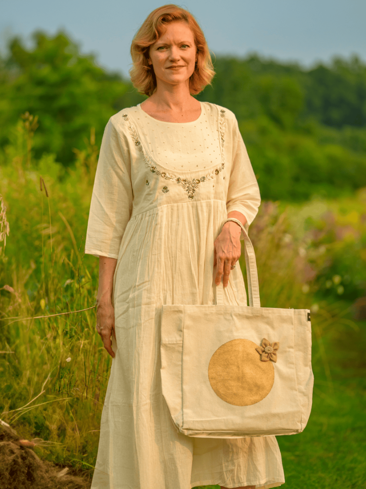 Woman in a light dress holding a matching tote bag