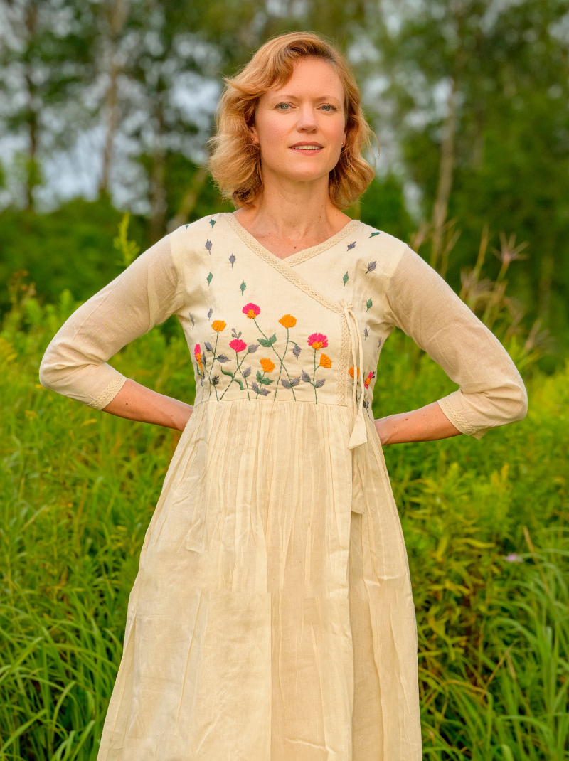 Woman wearing a beige dress with floral embroidery in a natural setting