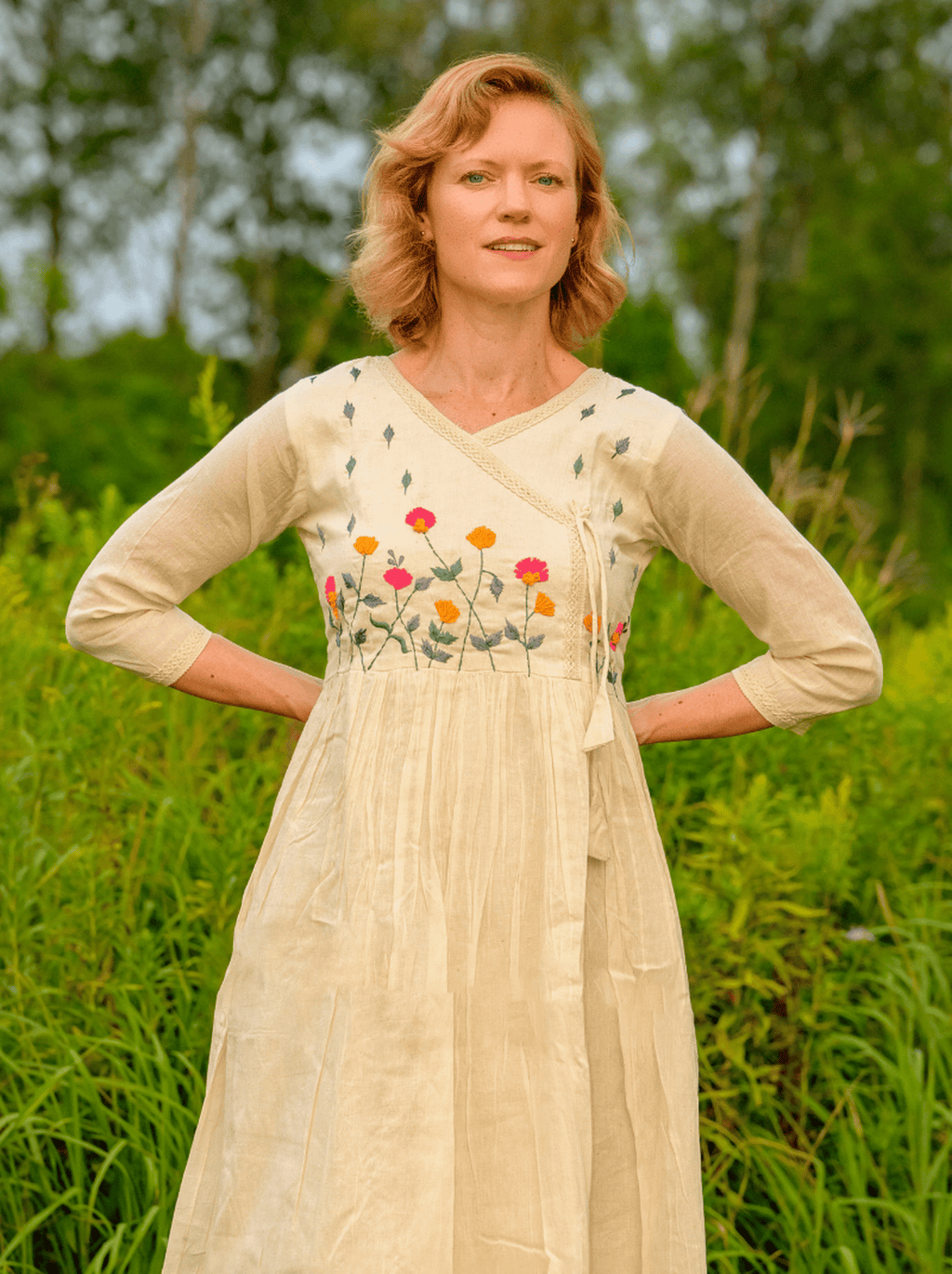 Woman wearing a beige dress with floral embroidery in a natural setting