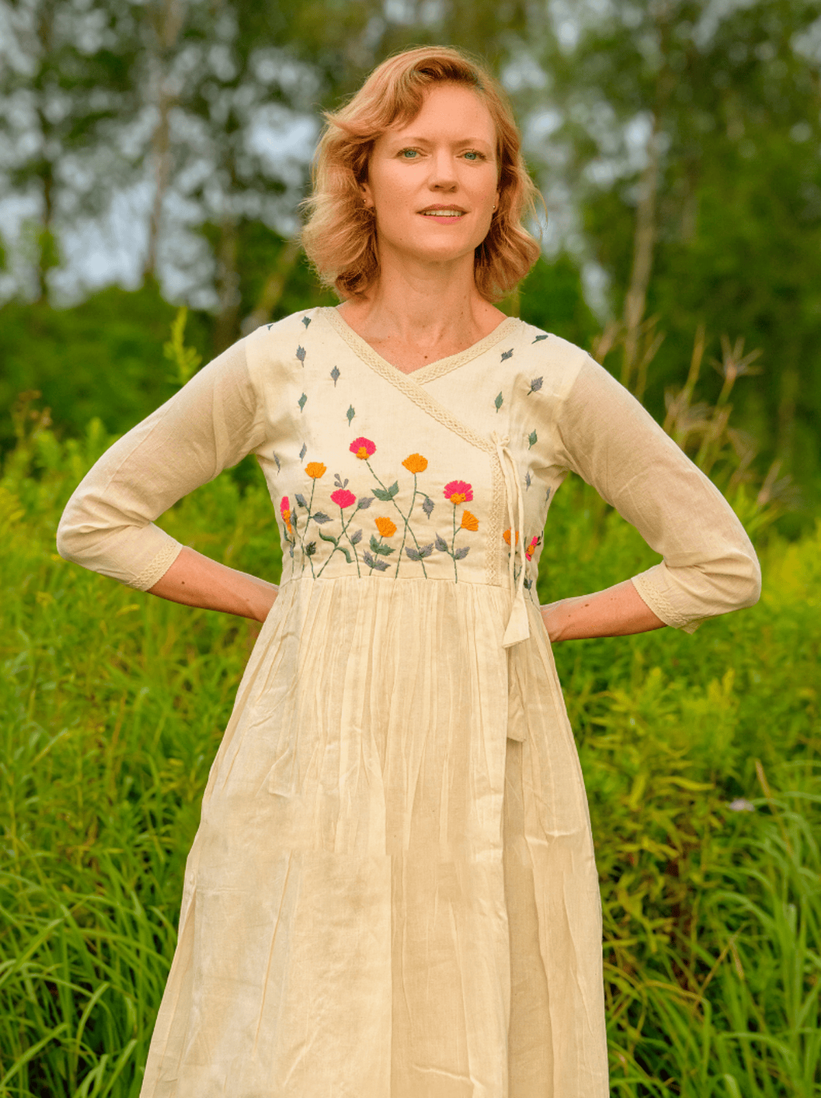 Woman wearing a beige dress with floral embroidery in a natural setting