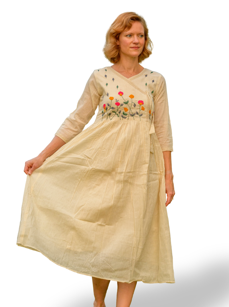 Woman wearing a beige dress with floral embroidery on a white background