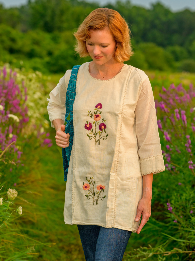 Woman in a floral embroidered dress standing in a field of flowers