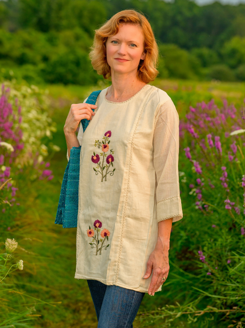 Woman wearing a beige embroidered top in a field of flowers