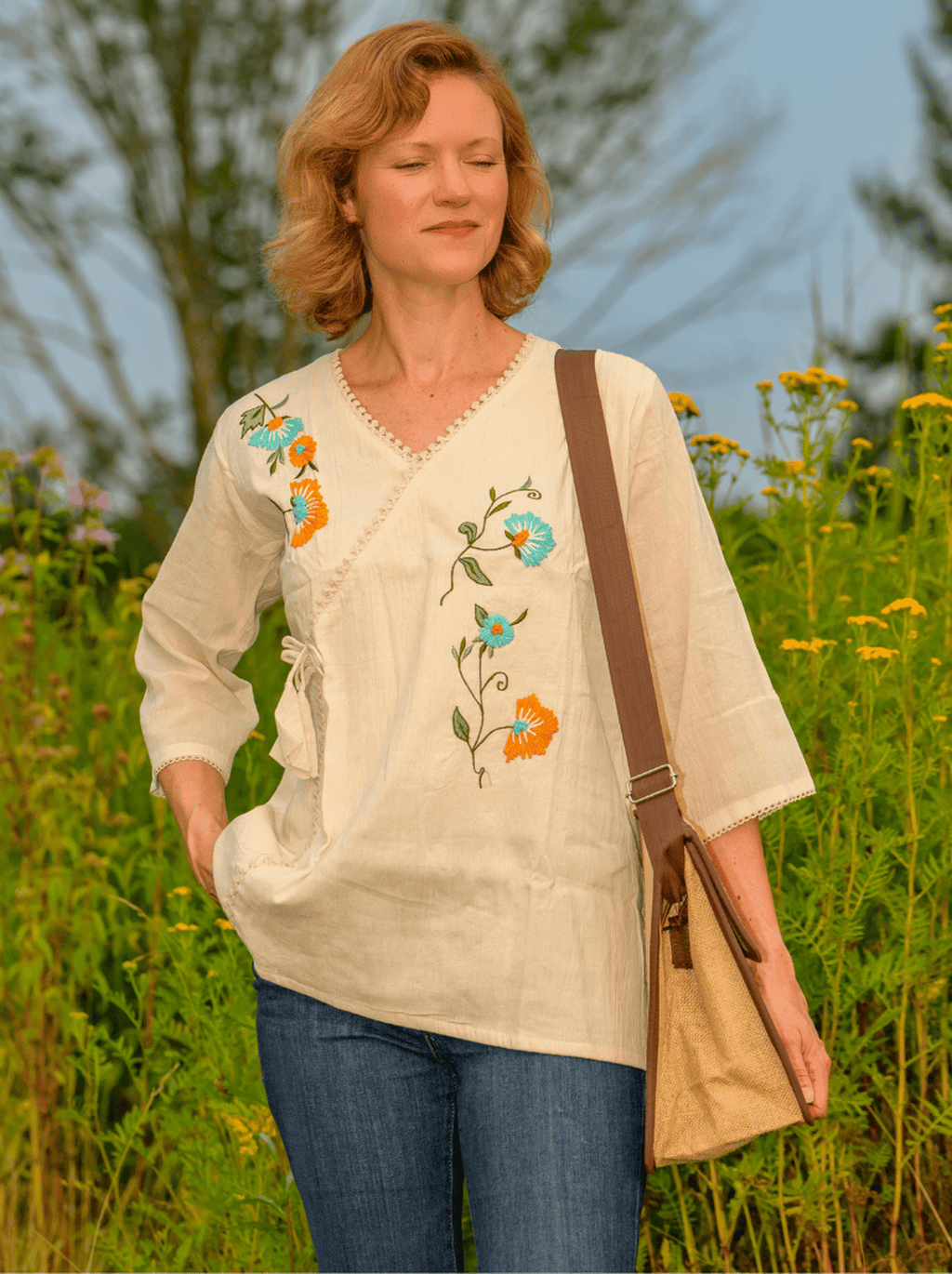 Woman wearing a cream-colored blouse with floral embroidery in a field
