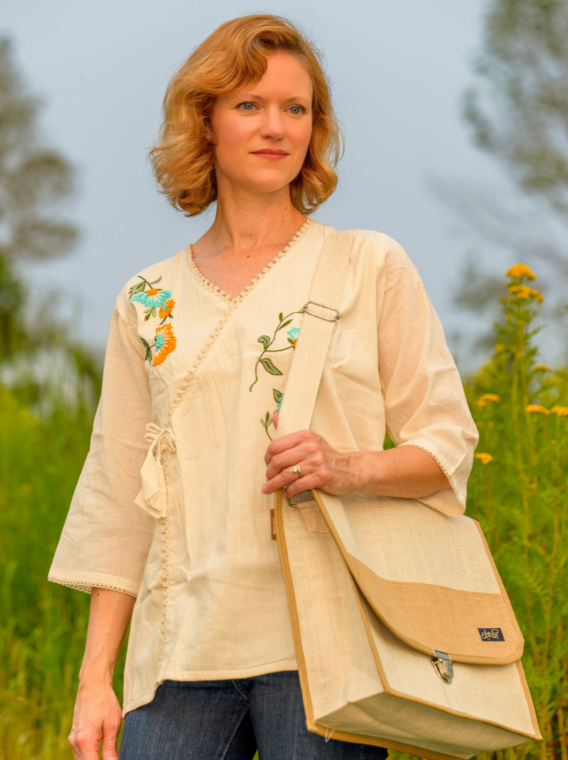 Woman holding a beige bag with floral embroidery in a natural setting